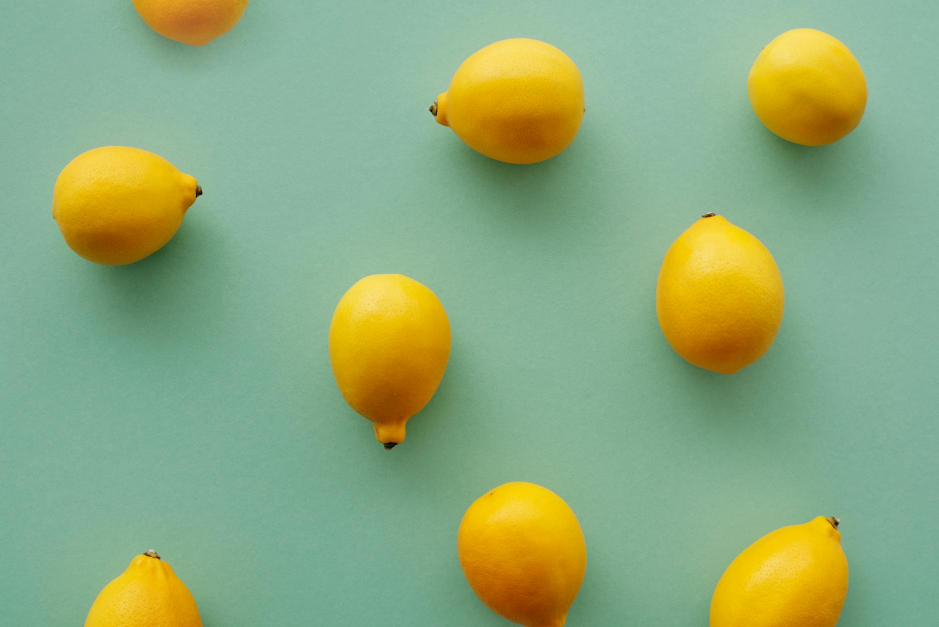 Bright yellow lemons arranged on a pastel green background, symbolizing freshness and renewal