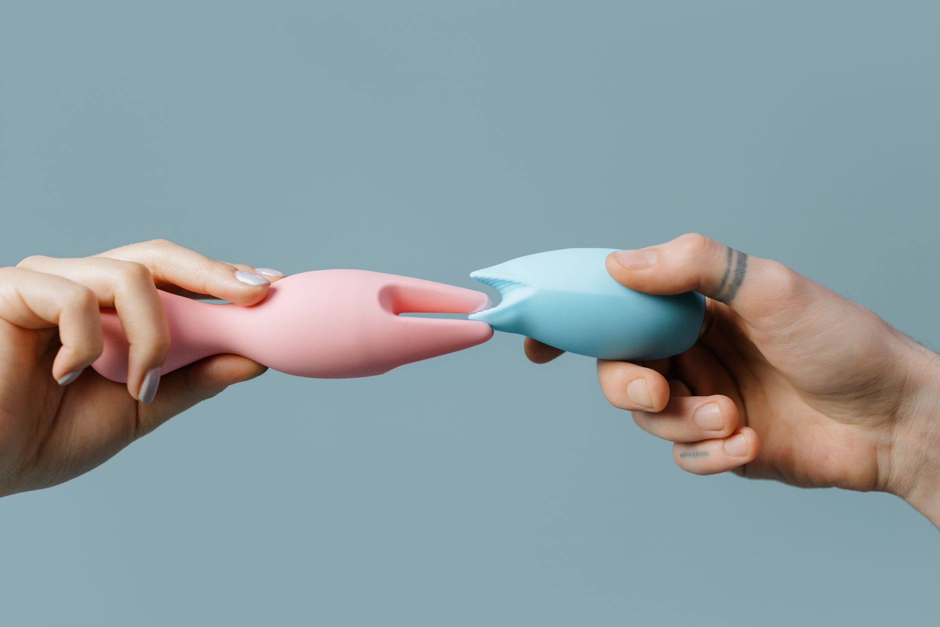 Hands holding pastel-colored vibrators together, symbolizing shared intimacy and reconnection