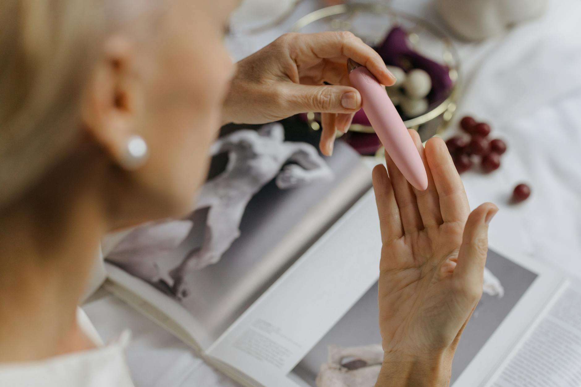 Woman holding blue and pink silicone vibrators in a contemplative manner, exploring intimate wellness options