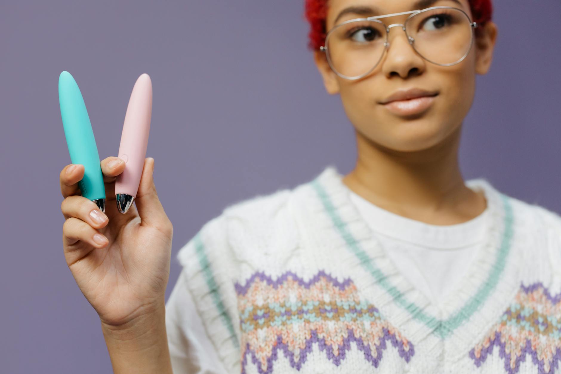 Woman holding colorful vibrators against purple background, representing postpartum pleasure options