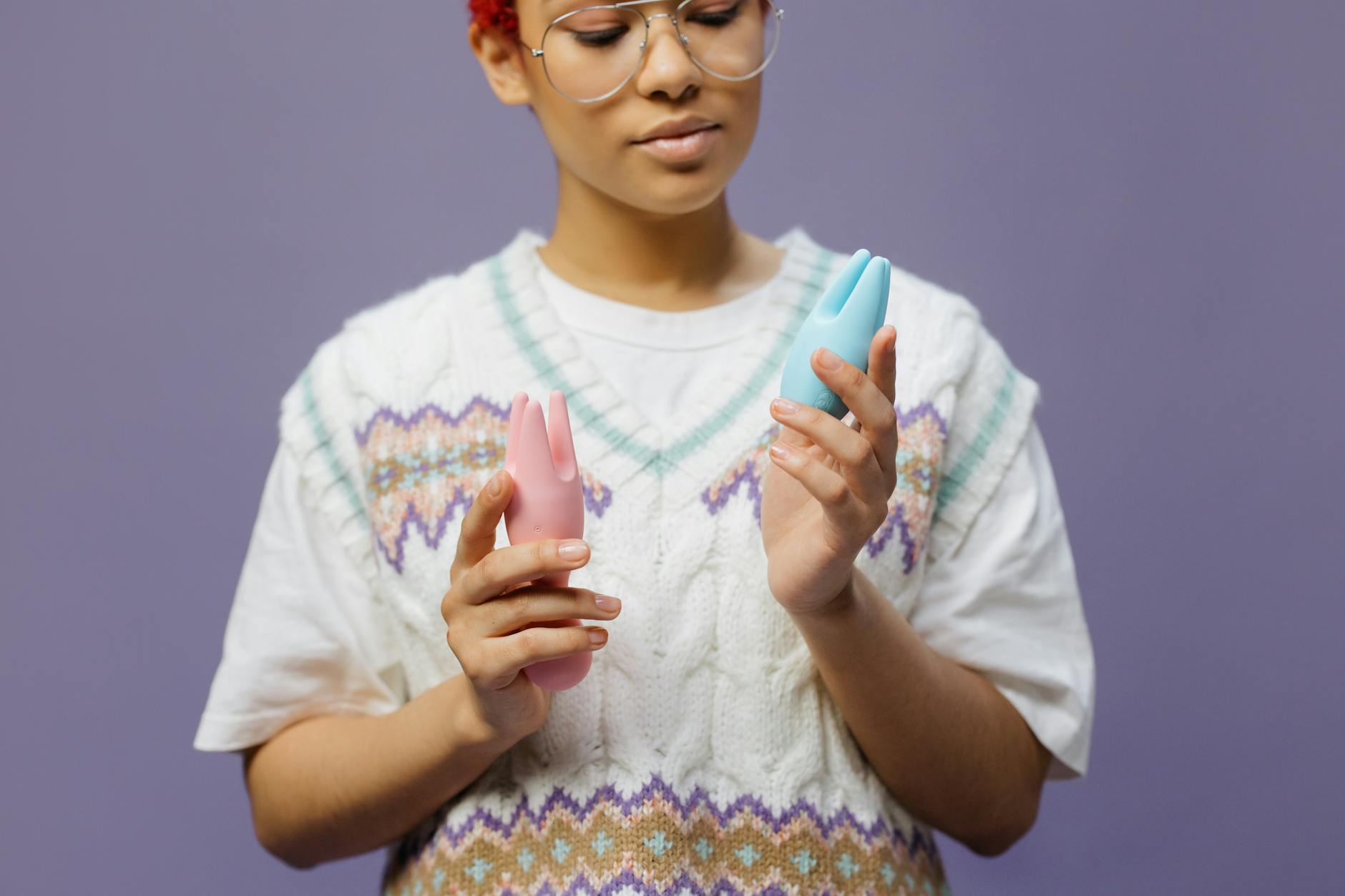 Woman holding blue and pink silicone vibrators in contemplation after divorce recovery