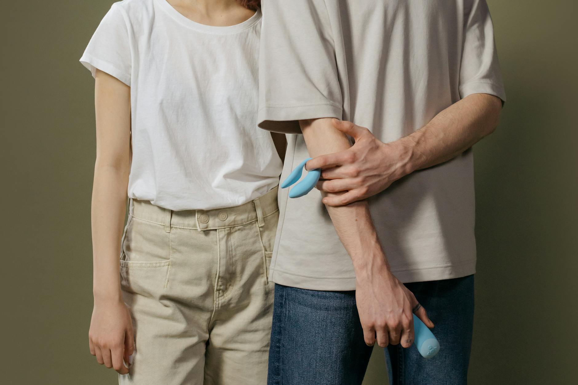Blue silicone vibrator held in hand against a purple background, representing self-directed pleasure and intimacy